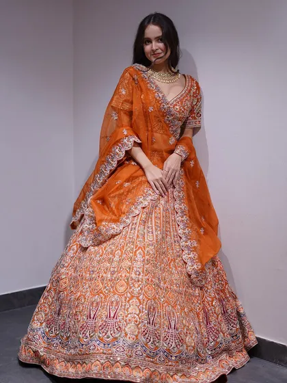 This heavily embroidered orange lehenga is a burst of sunshine for your wedding day. The detailed craftsmanship and vibrant color ensure all eyes will be on you.