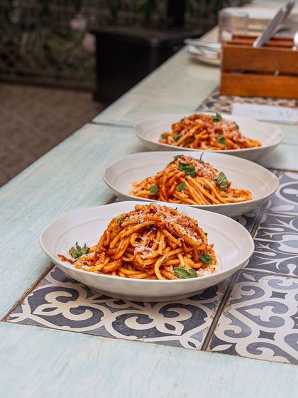 Three plates of perfectly twirled pasta, coated in a rich tomato sauce and ready to be served at our Amalfi Sunday Brunch.