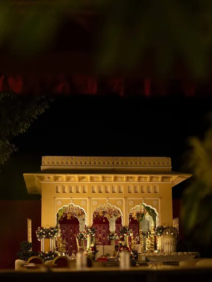 A distant view of the wedding mandap at night, set up in the palace courtyard. This shows the scale of our productions within these grand heritage sites.