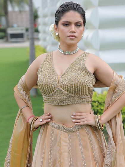 A powerful pose from the model in the beige and gold lehenga, showing its modern silhouette.