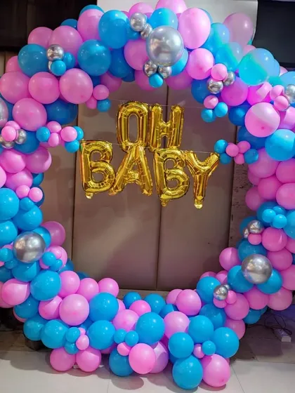 A vibrant and fun "Oh Baby" balloon ring. This full circle is covered in bright pink and blue balloons with silver accents, making it a perfect gender reveal or baby shower photo backdrop.