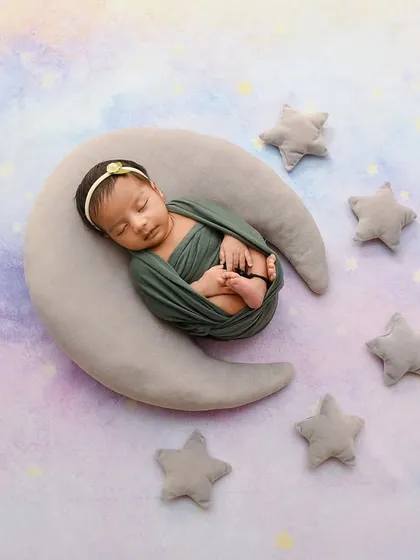 A serene portrait of a baby sleeping on a moon prop against a pastel, galaxy-like backdrop. This is another take on my popular celestial theme for newborn photography.
