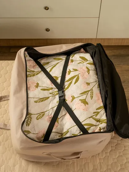An inside look at a Faborange storage bag, showing the internal straps securing a patterned quilt. This shot highlights the functional details of the product's design.