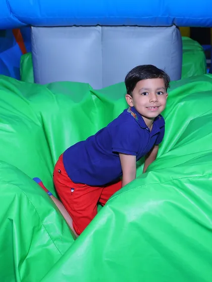Crawling through a world of green! A young boy explores one of our soft, inflatable play structures, perfect for imaginative and active fun.