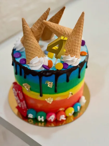 A different angle of the fun rainbow and ice cream cone cake, showing the personalized name at the base.
