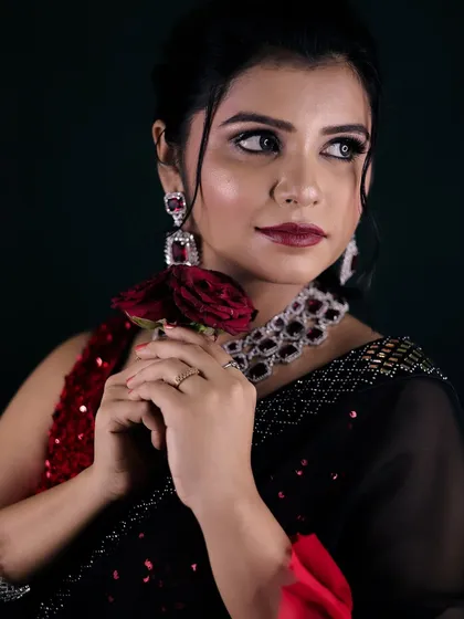 A dramatic and romantic party look. The red rose adds a touch of classic glamour to the modern black saree and diamond jewelry.