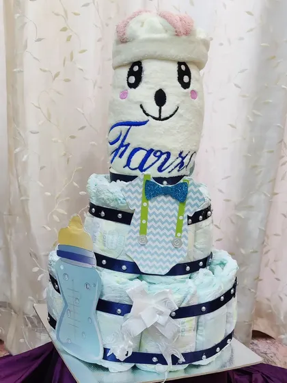 How cute is this diaper tower for a new baby boy? It’s a creative and practical gift for a baby shower, built with diapers and topped with a cozy blanket embroidered with the baby's name.