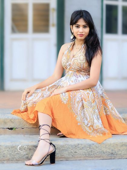 A full-length seated portrait that showcases the beautiful drape of the dress and her elegant posture.