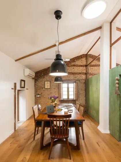 The conference room in our studio features a long wooden table set against an exposed brick wall. The industrial-style pendant lights and vaulted ceiling maintain the building's original character while creating a functional space for team meetings and client presentations.