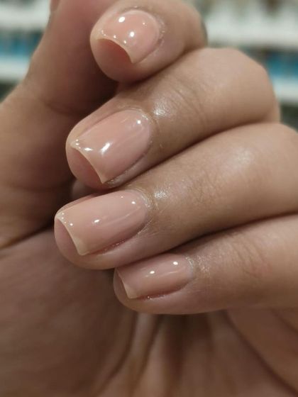 This image showcases a beautifully done nude gel manicure on short, square-shaped nails. The color is a soft, natural pink that provides a clean and understated finish.