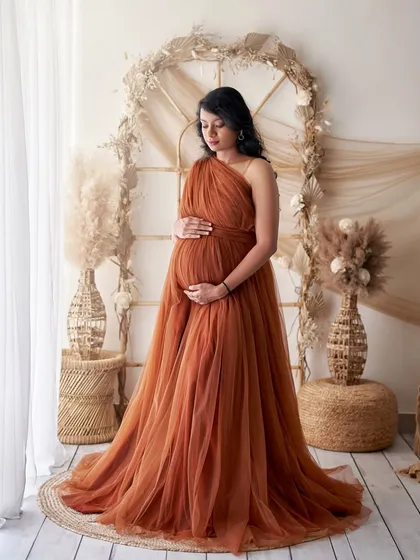 Embrace a natural, earthy vibe with our Copper gown. This look is perfect for our boho-themed studio setups, featuring pampas grass and wicker furniture for a warm and serene maternity session.