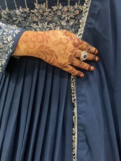 A close-up of a fresh floral henna design on the back of the hand. The details are sharp and the paste is smooth, which is essential for a clean final stain.