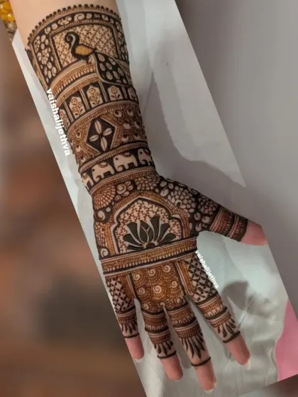 A stunning full-arm bridal piece with a prominent peacock, elephant band, and a central lotus motif.