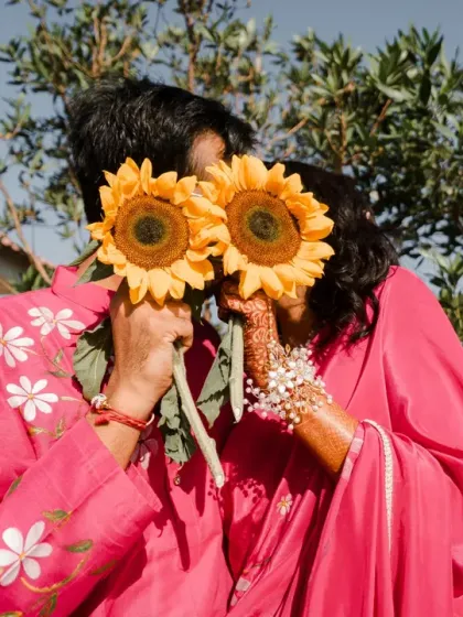 A playful and sweet photo where the couple hides behind sunflowers. This creative shot adds a touch of whimsy and romance to their Haldi album.