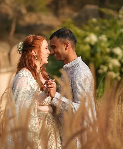 An intimate close-up of the couple, their foreheads touching, in a field of wild grass at their Alila Fort wedding.
