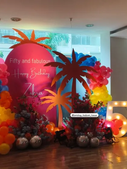 A vibrant "Fifty and Fabulous" tropical-themed party with large light-up numbers and colorful balloon arrangements.