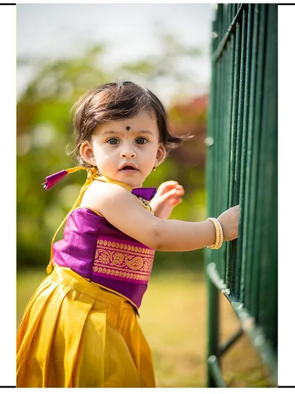 A candid shot of a toddler exploring her surroundings during an outdoor park photoshoot. Her traditional dress adds a beautiful pop of color.