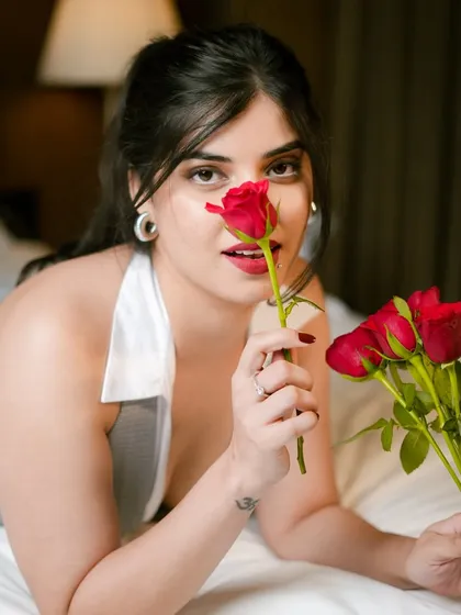 A playful yet romantic shot of Parul Mundra. The bright red lip and defined eyes are the centerpiece of this look, perfectly matching the red roses and the overall theme of the shoot.