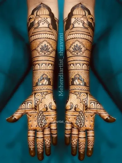 A beautiful example of symmetrical bridal mehendi. The design is balanced with lotus motifs on the forearms and elegant paisley teardrops on the palms.
