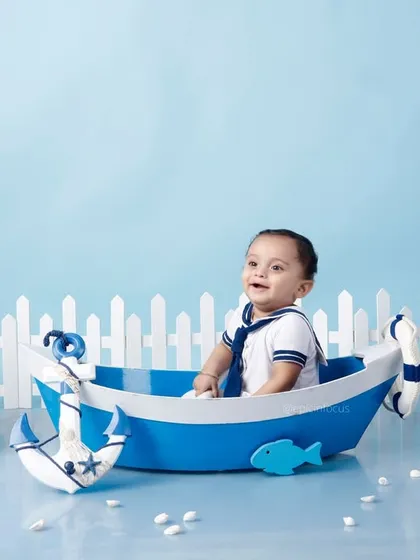 A happy little sailor in our nautical-themed setup. The crisp blue and white colors, along with props like a ship's wheel and lighthouse, create a classic maritime feel.