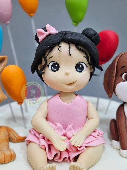 A detailed shot of the custom figurine for a 2nd birthday cake, capturing the sweet innocence of the little girl.