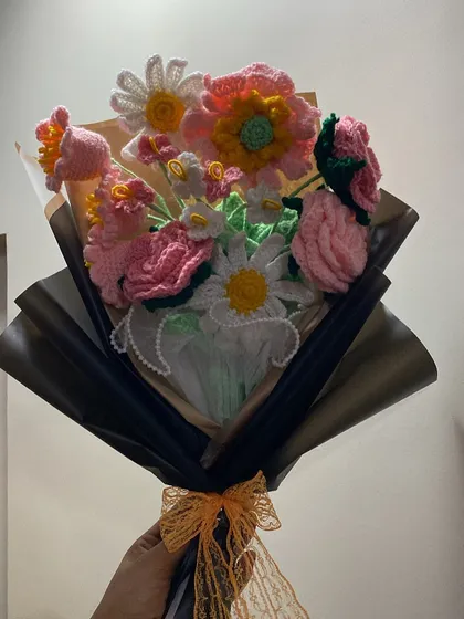 A beautiful mix of pinks, whites, and yellows. This bouquet features daisies, roses, and other flowers, wrapped in black paper for a striking contrast. Perfect for Valentine's Day or any special day.