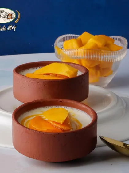 Our Baked Mango Yogurt is a healthier dessert option. Served in traditional clay pots, it's a creamy, tangy, and sweet treat topped with fresh mango slices.