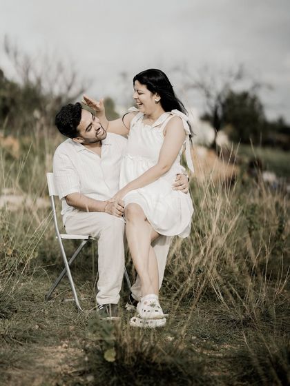 A playful interaction between a couple in a field, capturing a moment of laughter and fun.