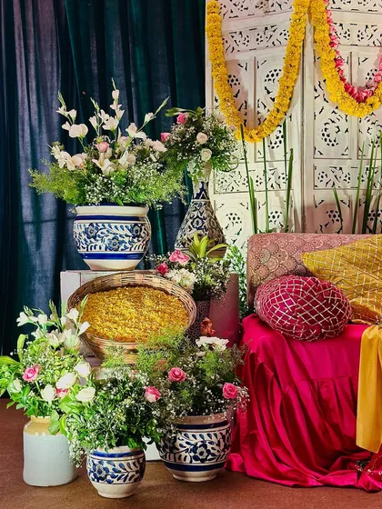 An assortment of floral arrangements and decor items for a Mehendi, including baskets of petals and flowers in traditional ceramic vases.