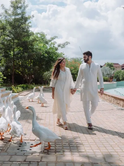 A whimsical and fun pre-wedding moment, as the couple takes a walk accompanied by a flock of friendly geese.