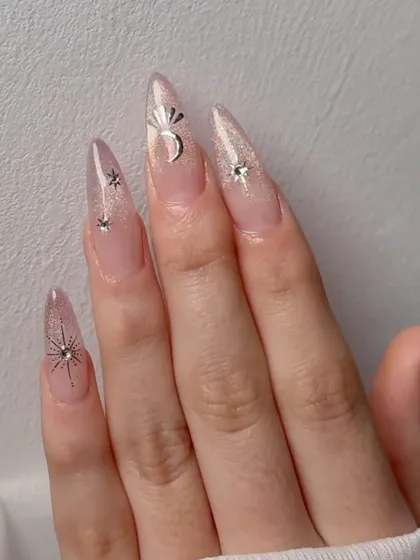 Minimalistic chic nail inspiration: a sheer cat eye base with delicate silver chrome stars and moons.