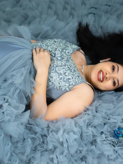 A creative perspective of our ruffled gown. This overhead shot shows the mom-to-be lying down, with the light blue fabric creating a beautiful, textured pattern around her.
