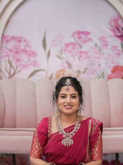 The bride looks serene and happy, seated in front of the custom-designed floral backdrop. The soft colors and romantic theme of the decor make for a beautiful portrait setting.