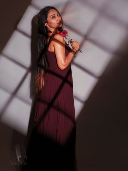 A portrait that plays with light and shadow, using a projected window pattern to create a sense of being both seen and hidden. The rose adds a touch of romance and fragility.