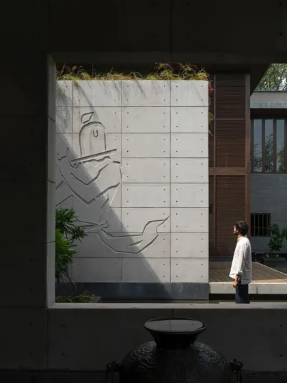 A custom art panel made of concrete is integrated into the architecture, depicting a traditional figure and showcasing the fusion of art and building.
