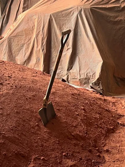 A pile of rich, red earth waits to be mixed and compressed into blocks for Aadi Villa. This image captures the fundamental, elemental nature of our material exploration.