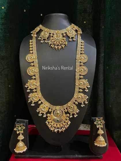 An elegant temple jewellery set with pearl drops and green stone accents.