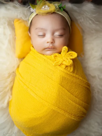 A close up on the baby's peaceful face, highlighting the soft textures of the wrap and the faux fur rug.