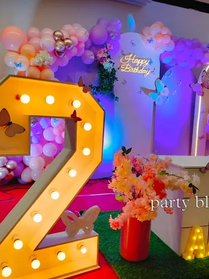 A close-up of the decor, showing the intricate details like small butterflies placed on the marquee number and the floral arrangements that complement the theme.