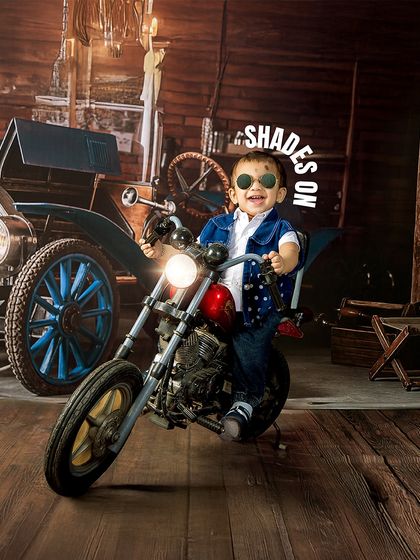 Shades on, ready to roll. This little biker strikes a cool pose with his sunglasses, fully embracing the rockstar vibe of the vintage motorcycle theme.