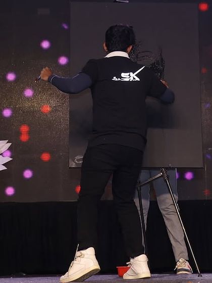 Here I am on stage, completely in the zone during a speed painting show at a school. The performance is accompanied by dancers with angel wings, adding to the spectacle.