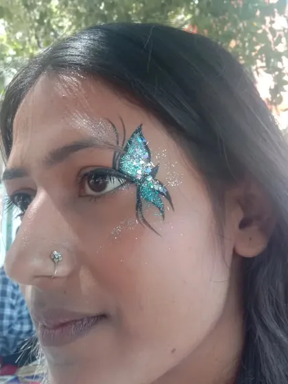 A close-up of one of my favorite butterfly designs. The vibrant teal glitter catches the light beautifully, and the fine black and white details make the design pop. I use only cosmetic-grade, skin-safe glitter for all my face painting.