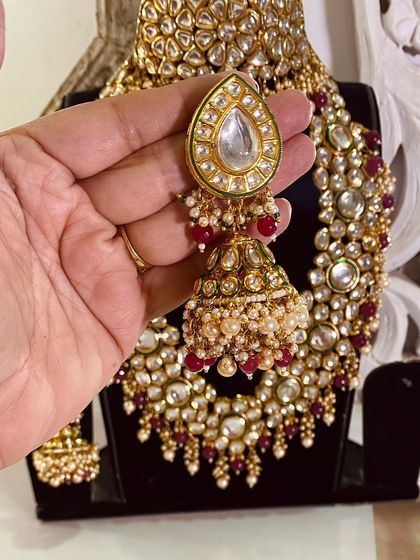 A close-up of a large kundan jhumka with ruby bead drops.