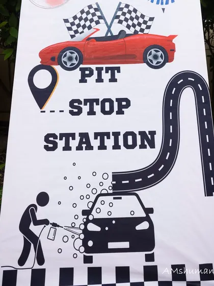 A "Pit Stop Station" sign with a car wash graphic, one of the fun activity signs for the party.