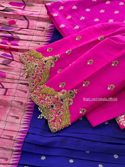 Richly embroidered sleeve cuffs in gold zardosi and blue stones on a bright pink blouse, paired with a deep blue and pink ikat-style saree.
