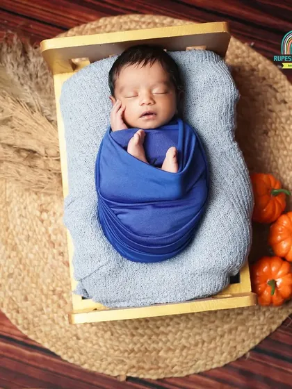 A newborn rests in a tiny bed on a rustic jute mat, surrounded by autumn-colored props. This demonstrates our use of natural textures and colors.