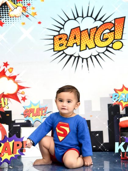 A close-up of our little Superman. The dynamic background with classic comic exclamations adds to the fun and energy of the shoot.