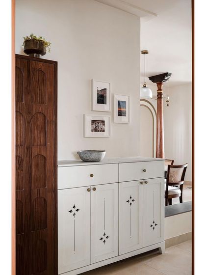 The foyer of the 'Kanasu' home sets a nostalgic tone with frames showing life in Mangalore. A vintage-style cabinet with antique handles embodies the harmony of old-world charm and contemporary functionality.