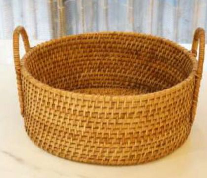 A round, tightly woven rattan basket with sturdy handles. Its classic design and durable construction make it an excellent choice for a market basket, a log holder by the fireplace, or for general home storage.