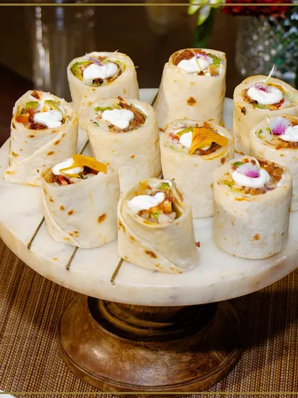 Bite-sized tortilla wraps served on a marble platter. These are a perfect example of our creative and convenient canapés, ideal for mingling guests.